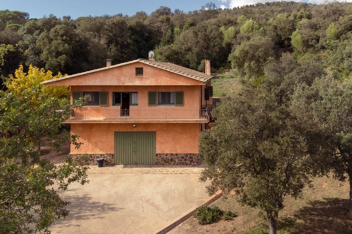 A two-story house with a green door, a balcony, and a stone foundation.