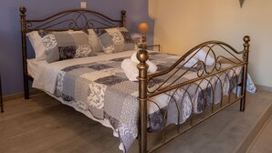 A bed with a metal frame, a bedside lamp, and a wall-mounted mirror. - Galini Apartment (Rhodes)