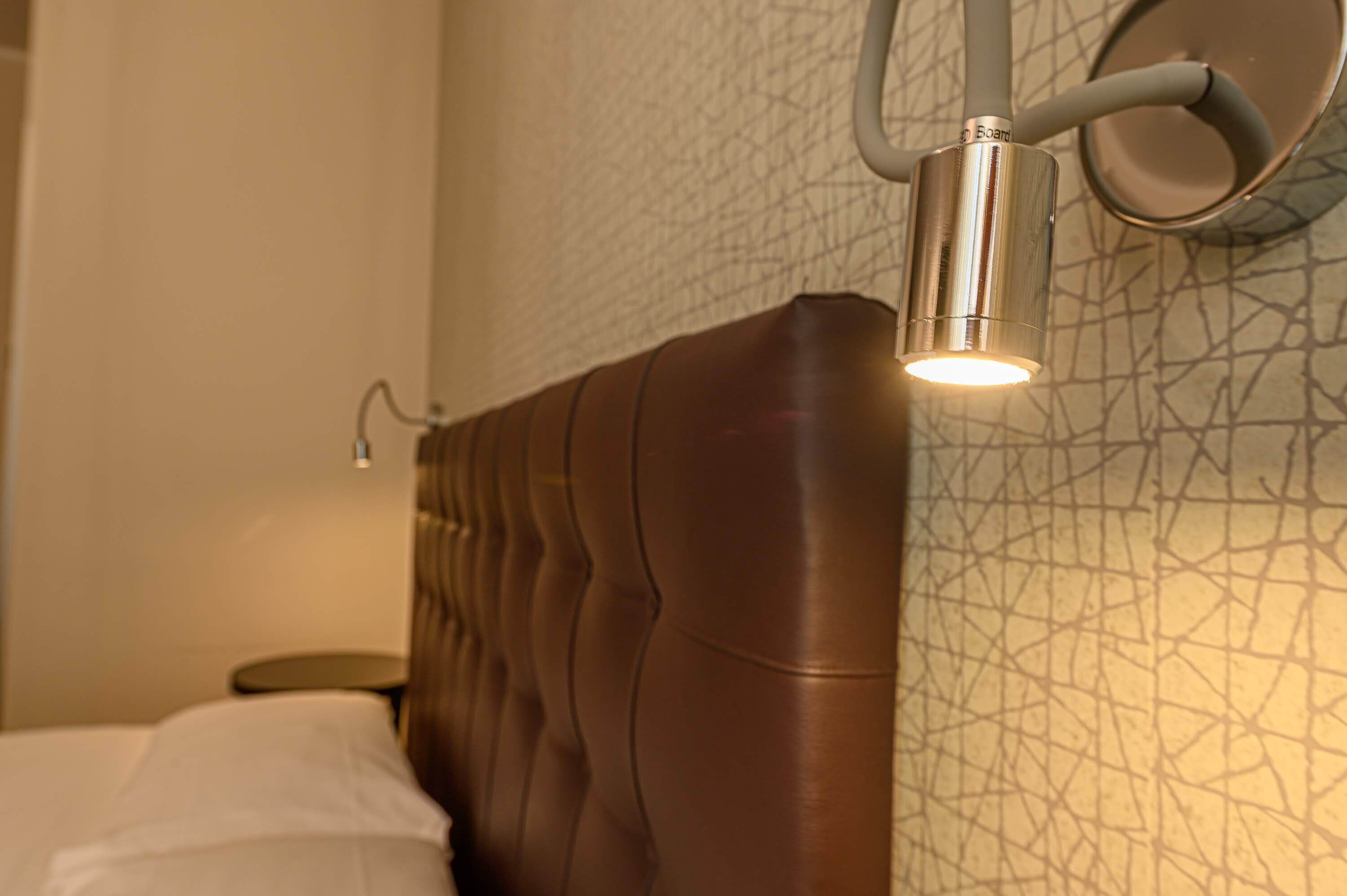 A modern room with a textured wall, a brown upholstered headboard, and a small bedside table.
