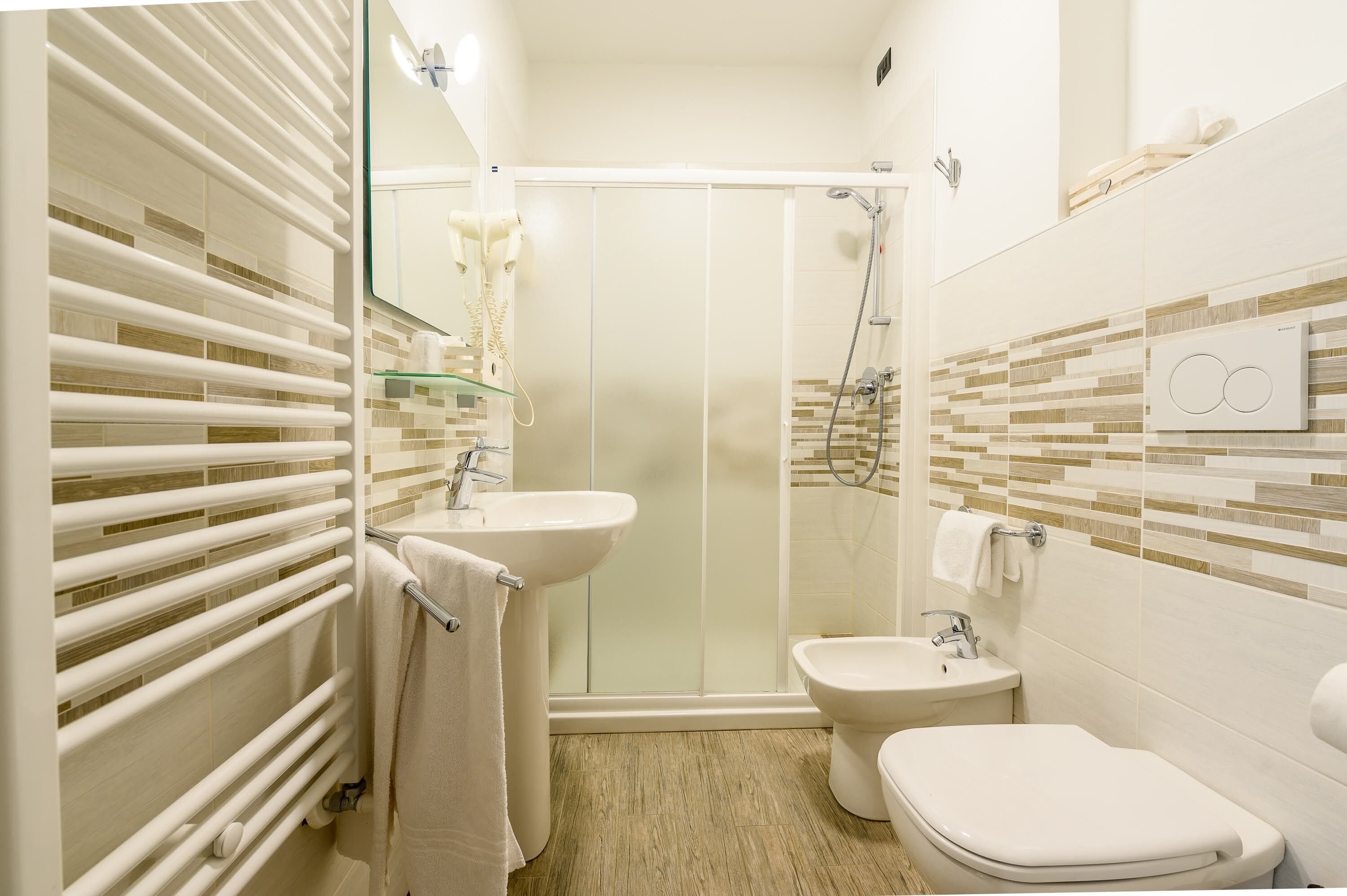 Ein modernes Badezimmer mit Duschkabine aus Glas, Waschbecken, Toilette und Handtuchhalter.