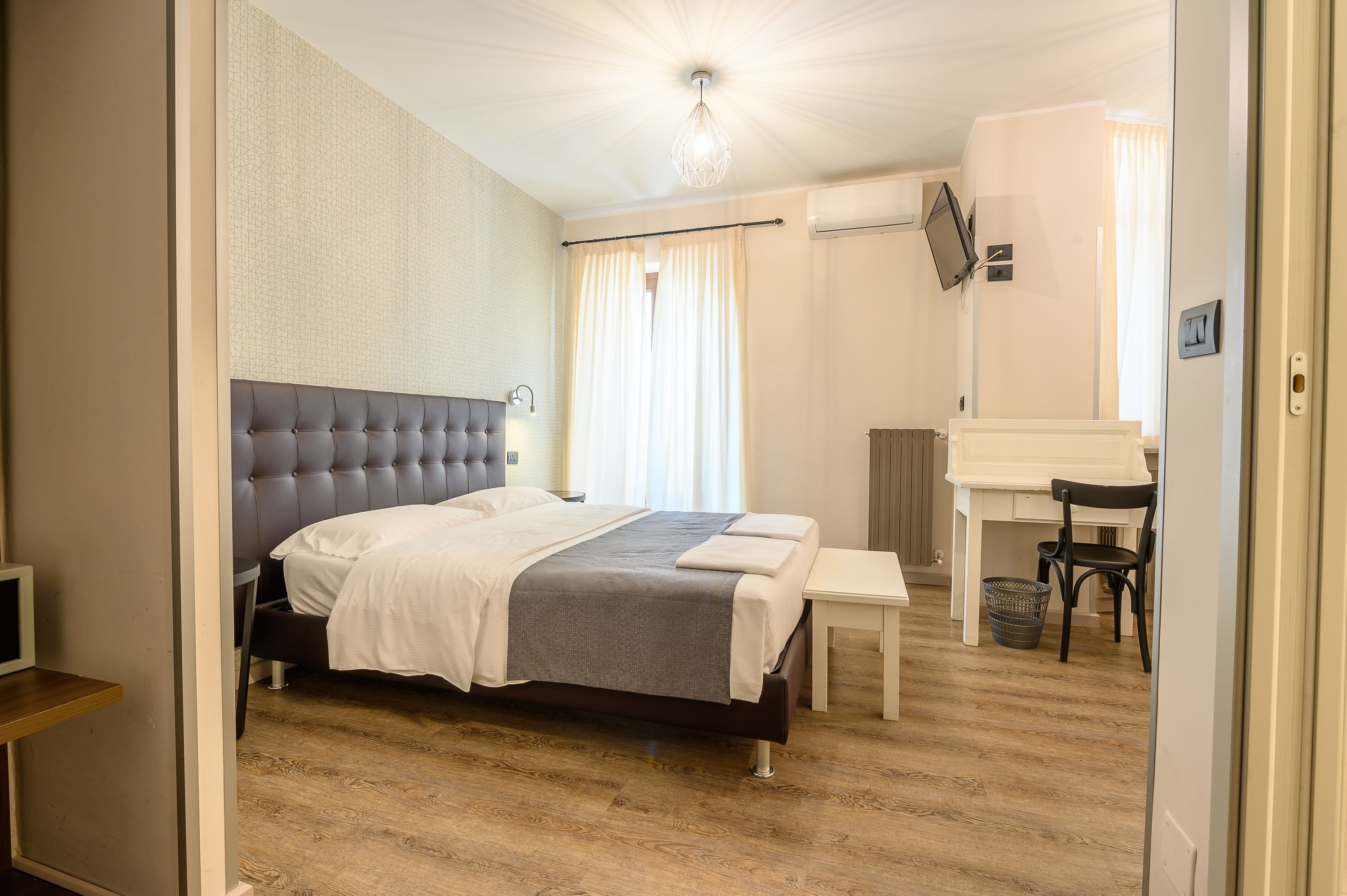 Une chambre à coucher comprenant un lit, un bureau, une chaise et un téléviseur.