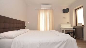 Una camera da letto con un letto, una scrivania, una sedia, un climatizzatore e una televisione.