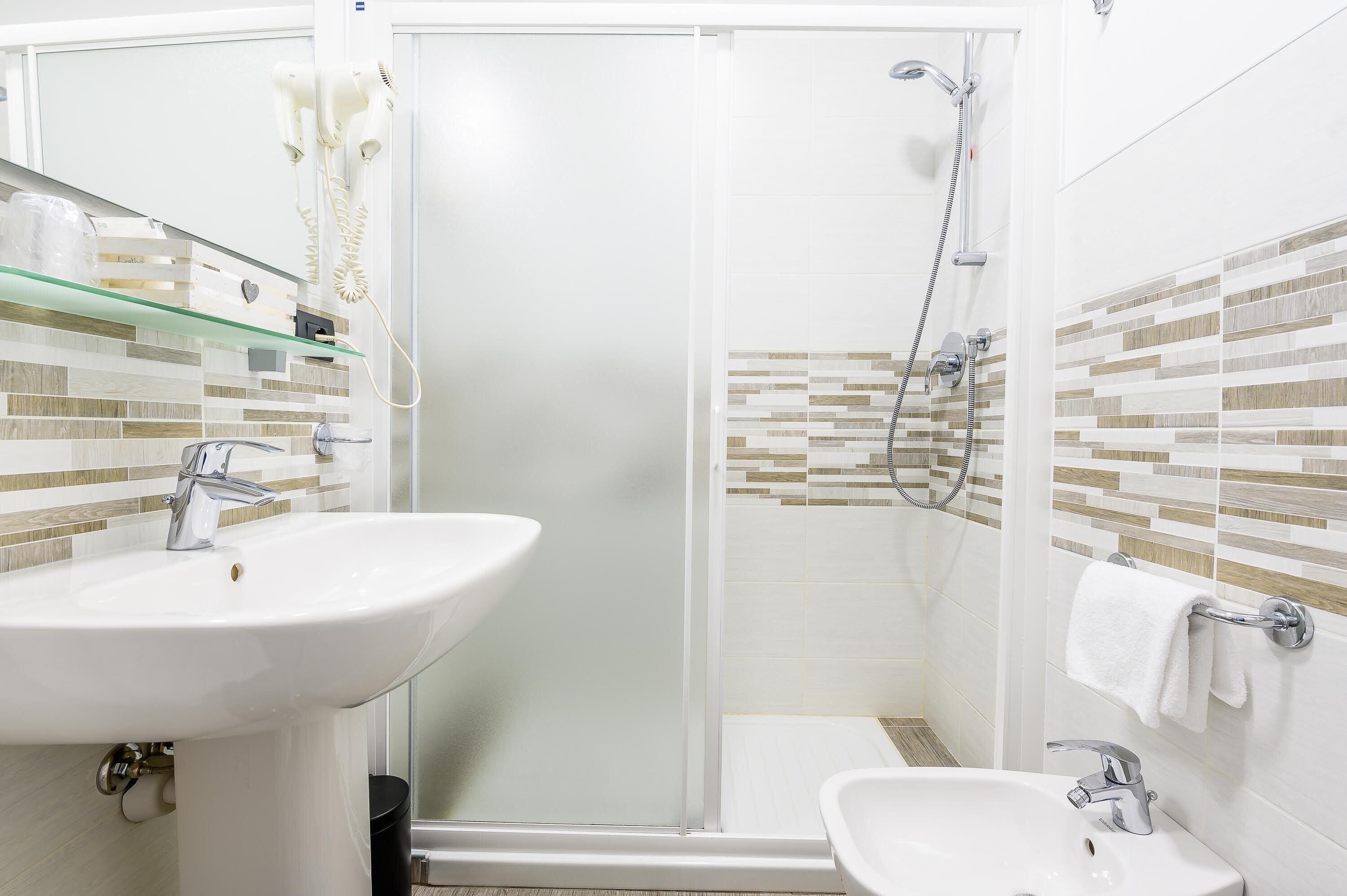 A bathroom with a glass-enclosed shower, a sink, and a towel rack.
