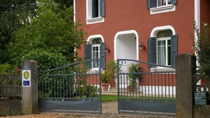 A gated entrance with a metal gate, a red building with white trim, and a sign with the number 33. - L'Oustalet D'Anicette (Valence)