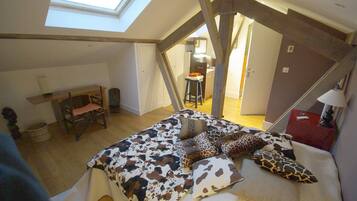 Une chambre avec un plafond en pente, un puits de lumière, un lit avec une literie à motifs, un bureau et une chaise.