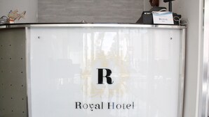 A reception desk at the Royal Hotel with a prominent 'R' logo and the hotel's name. - Hotel Royal (Porto Cesareo)