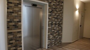 A hallway with a tiled wall and a wooden floor. - Hotel Royal (Porto Cesareo)