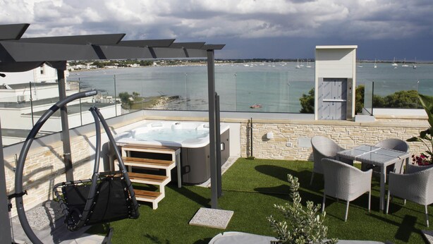 A rooftop terrace with a hot tub, outdoor seating, and a view of the sea. - Hotel Royal (Porto Cesareo)