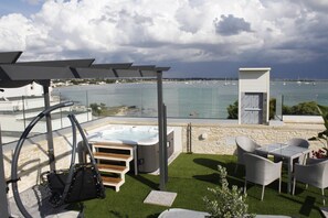 A rooftop terrace with a hot tub, outdoor seating, and a view of the sea. - Hotel Royal (Porto Cesareo)