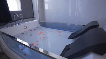 A modern bathroom with a large bathtub, a shower area, and a window with a mesh screen.