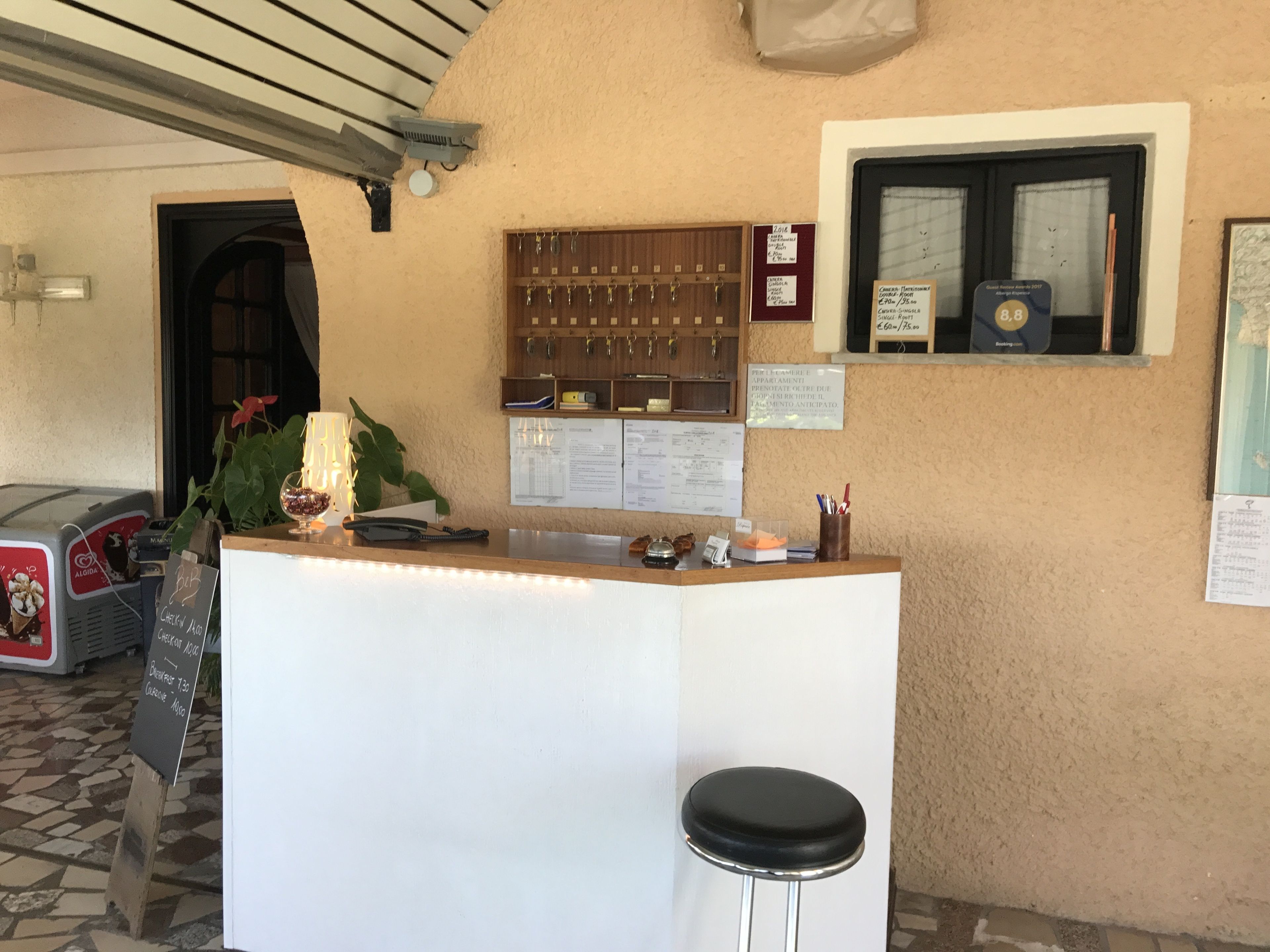A reception area with a counter, a phone, a menu board, and a window with a view.