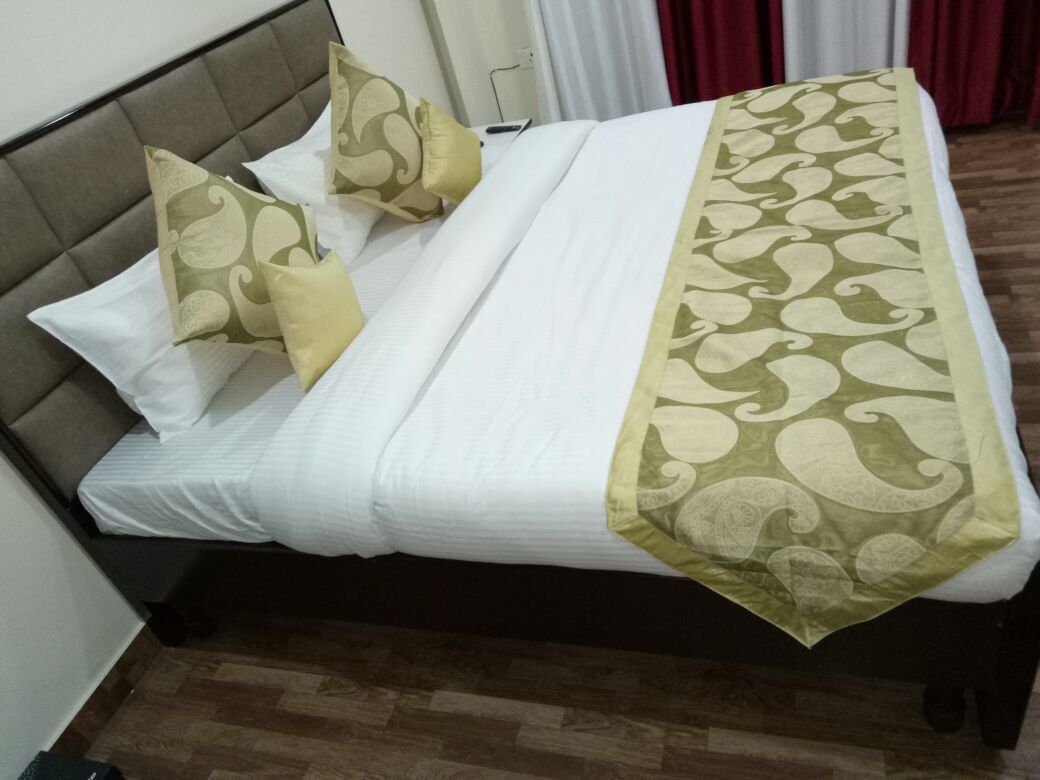 Ein ordentlich bezogenes Bett mit weißer Decke und einem gemusterten Überwurf.