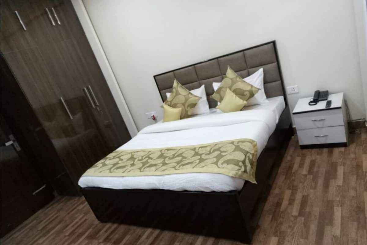 Una cama bien hecha con una colcha estampada, una mesita de noche con un teléfono y un armario.