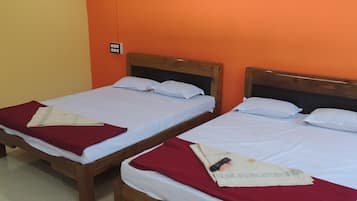 Two single beds with wooden frames and white bedding, set against orange walls, in a room with a tiled floor.