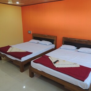 Two single beds with wooden frames and white bedding, set against orange walls, in a room with a tiled floor. - Mysa - Dandeli Lodge (Haliyal)