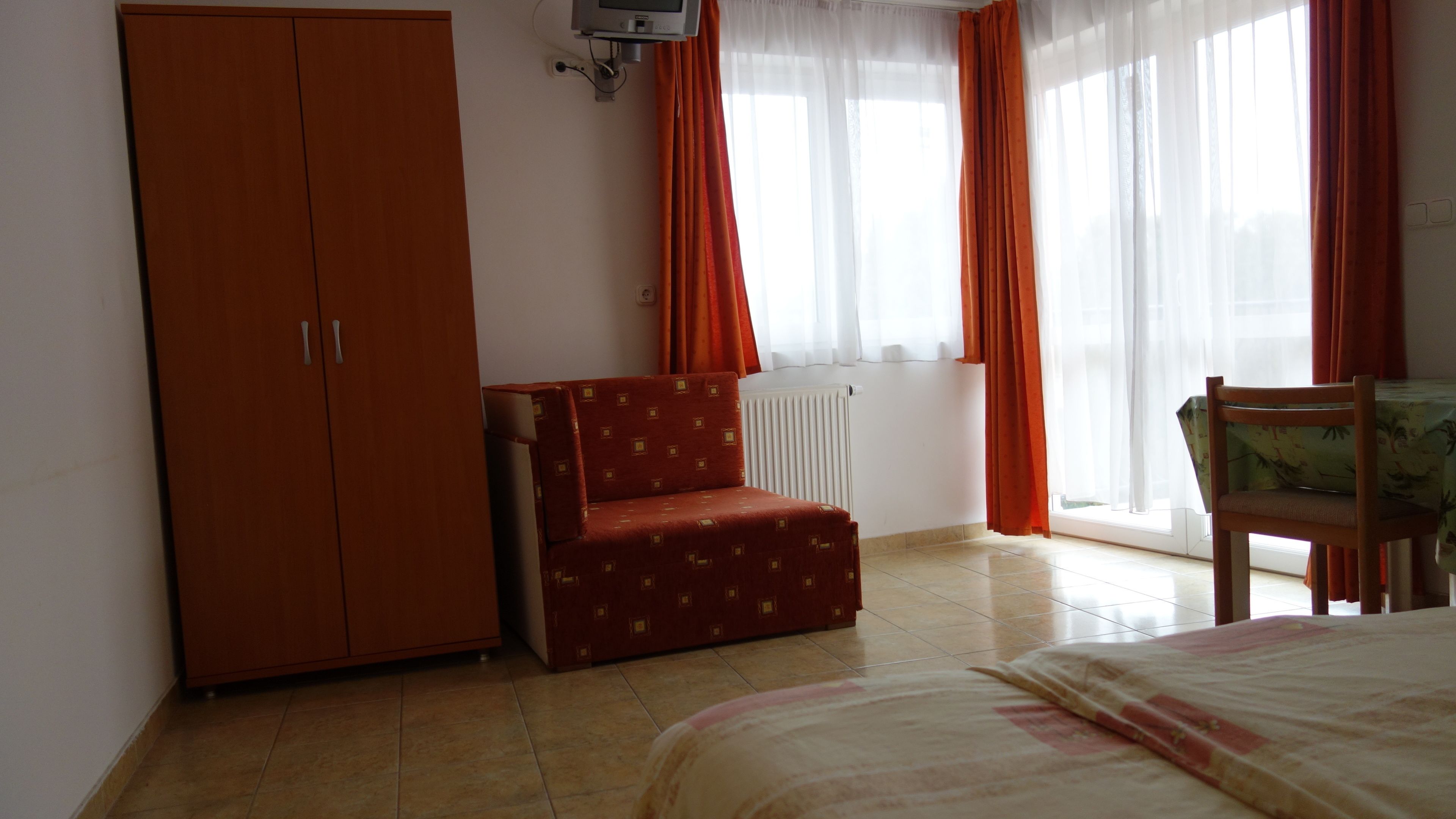 Quarto com cama, guarda-roupa, cadeira e radiador.