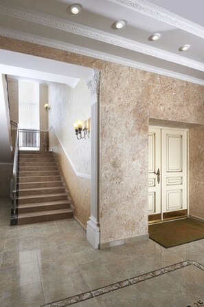 Stunning grand entrance with a marble staircase, ornate door, and elegant tile design.