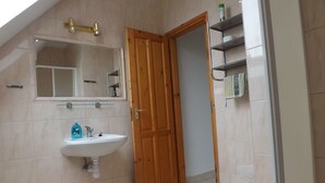 Een badkamer met een wit wastafelmeubel, een spiegel en een houten deur.