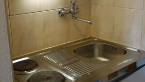 Een keuken met een roestvrijstalen spoelbak, twee kookplaten en een magnetron.