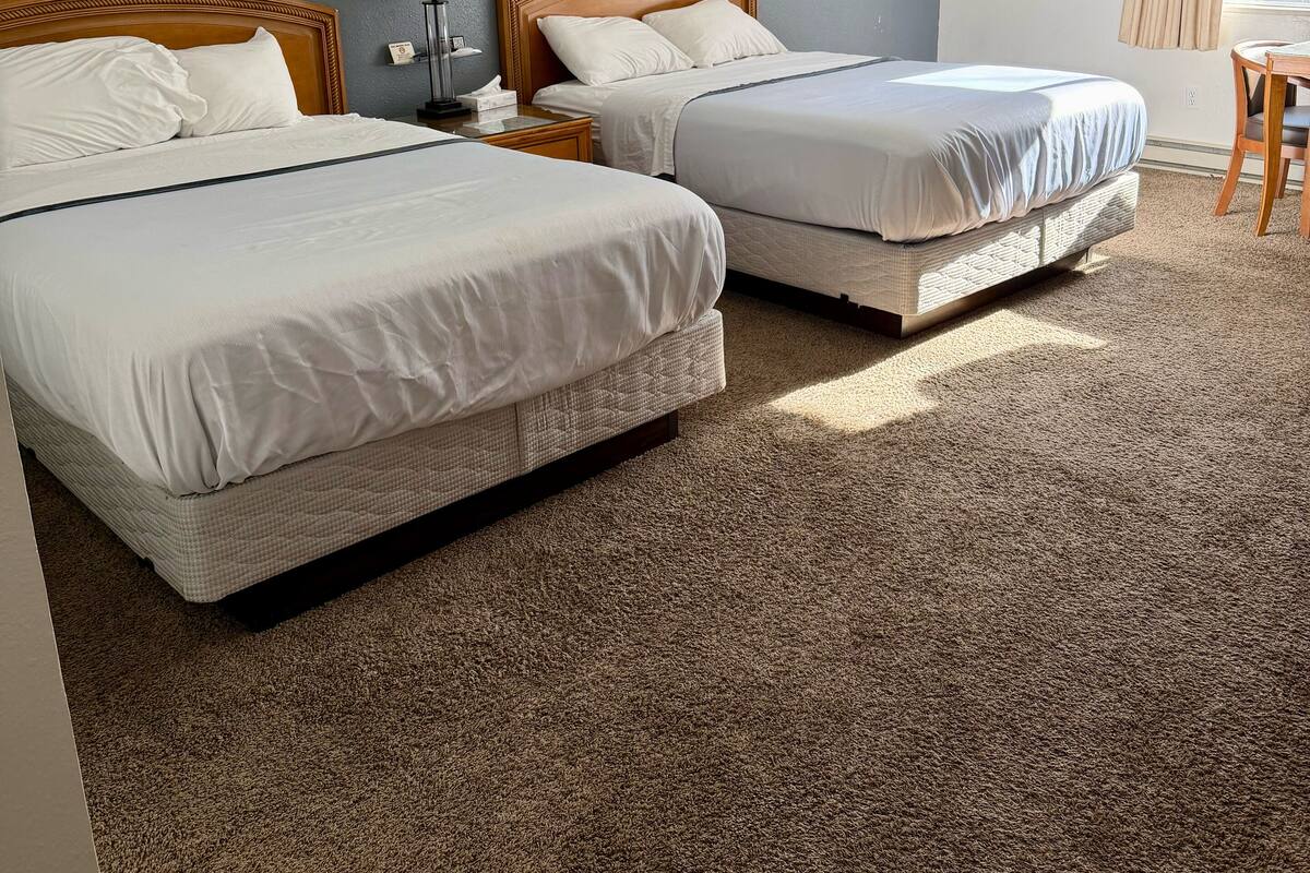 Habitación de hotel con dos camas, un escritorio y una silla.