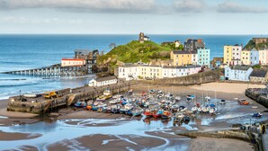 A coastal town with colorful buildings, a pier, and a historic tower. - Royal Lion Hotel (Tenby)