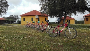 A row of bicycles parked in front of a yellow building with a red roof. - Albergue Turistico Cornalvo - Hostel (Trujillanos)