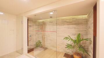 Enjoy a refreshing shower in this bathroom with a glass enclosure and stone-textured wall.