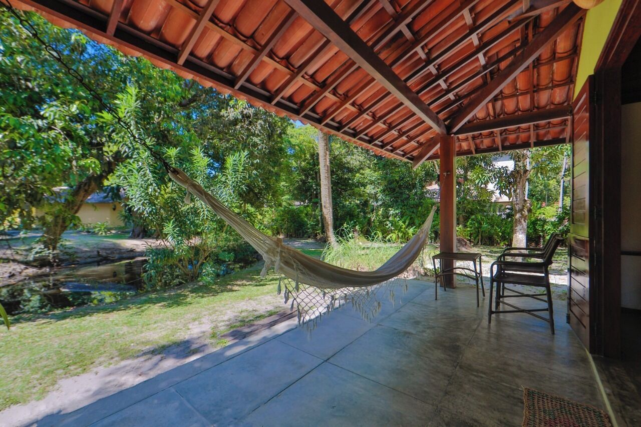 A covered outdoor area with a hammock, chairs, and a concrete floor.