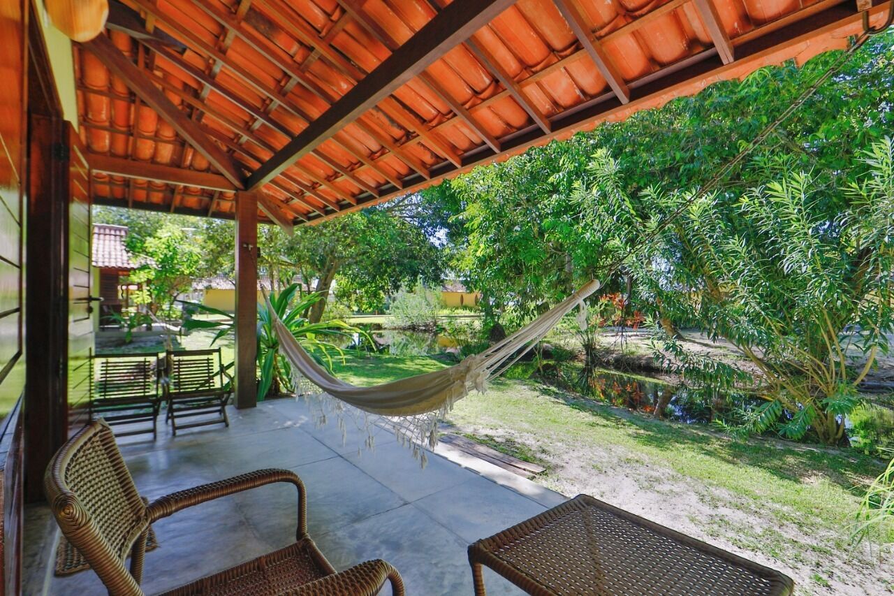 A covered outdoor area with wicker furniture, a hammock, and lush greenery.
