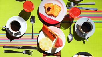 A table set with breakfast items including scrambled eggs, pancakes, toast, fruit, and beverages.