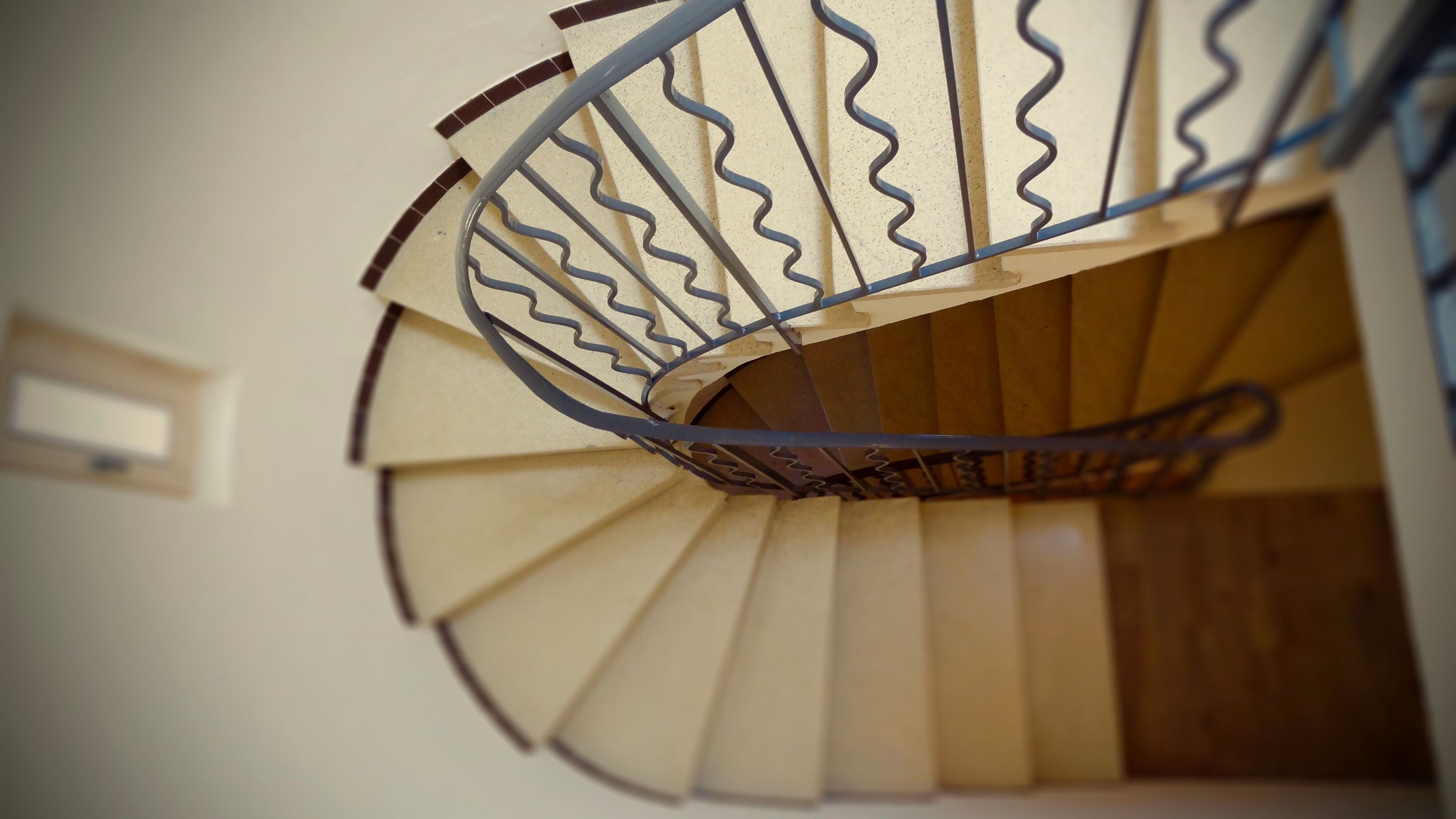 Gradi espirals amb barana metàl·lica i graons de fusta.