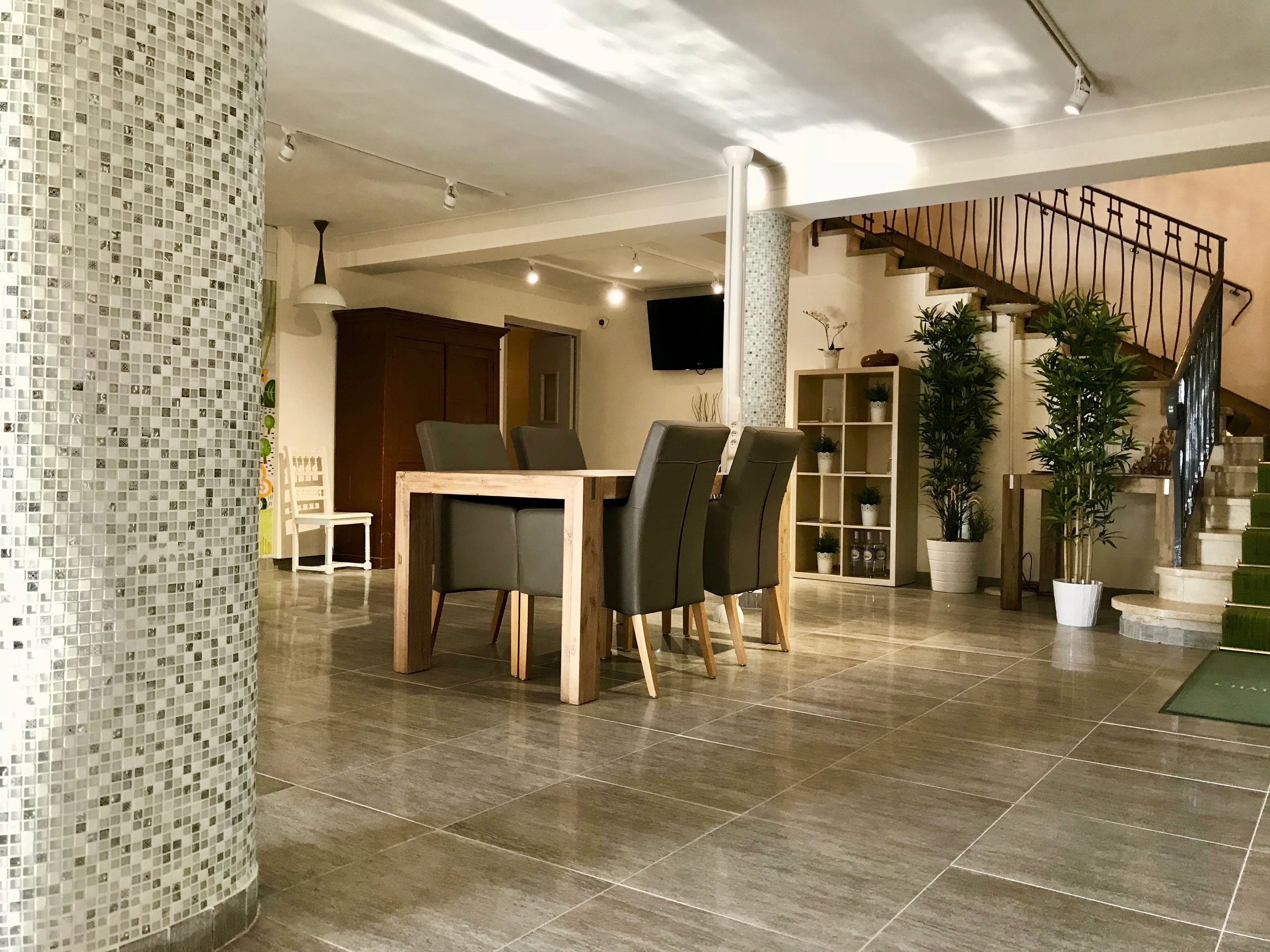 A modern interior with a dining area, staircase, and potted plants.