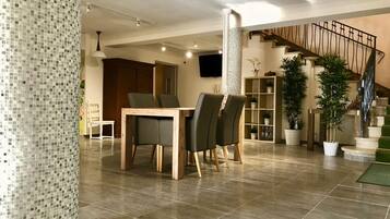 A modern interior with a dining area, staircase, and potted plants.