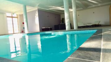 An indoor swimming pool with clear water, tiled walls, and a ceiling with natural light.
