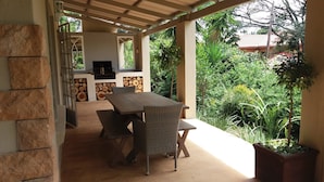 Une terrasse extérieure avec une table et des chaises, un téléviseur et une pile de bois de chauffage.