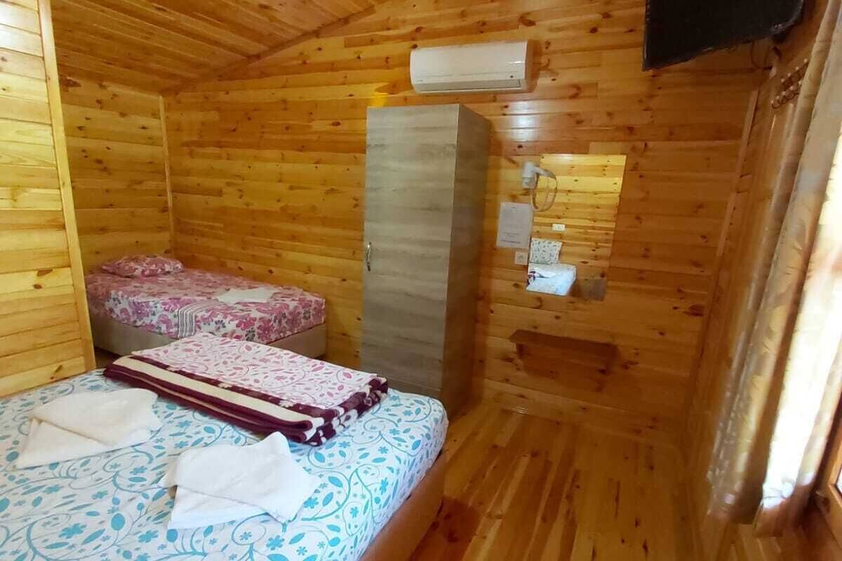En stuga med träpanel, inredd med en säng, en garderob och en TV som är monterad på väggen.