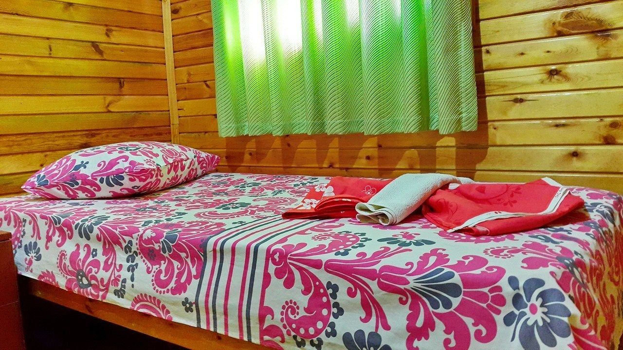 A single bed with a floral bedspread, a pillow, and a folded towel.