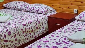 A wooden cabin room with two beds, an air conditioner, and a wall-mounted light fixture. - Olympos Tatilya Pansiyon (Kumluca)