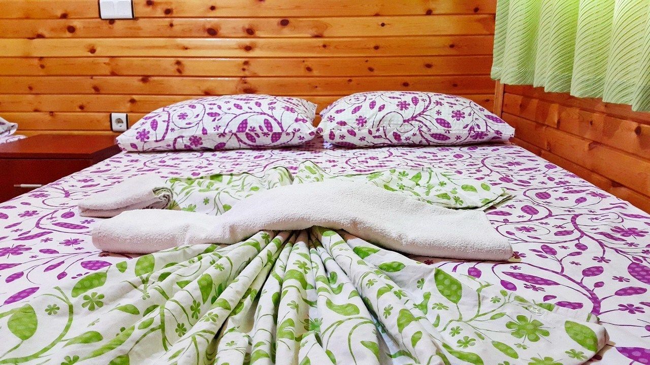 A wooden-paneled room with a bed, two pillows, and a blanket.