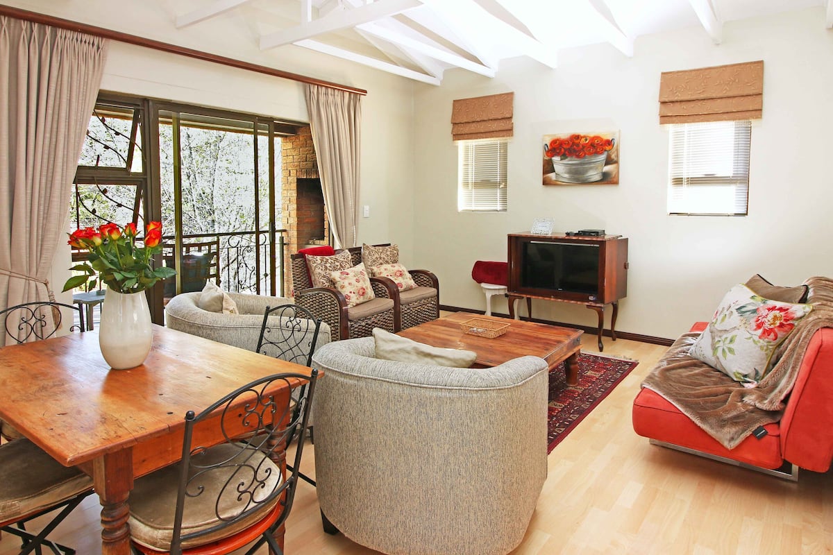 A living room with a wooden table, a sofa, a chair, and a television.