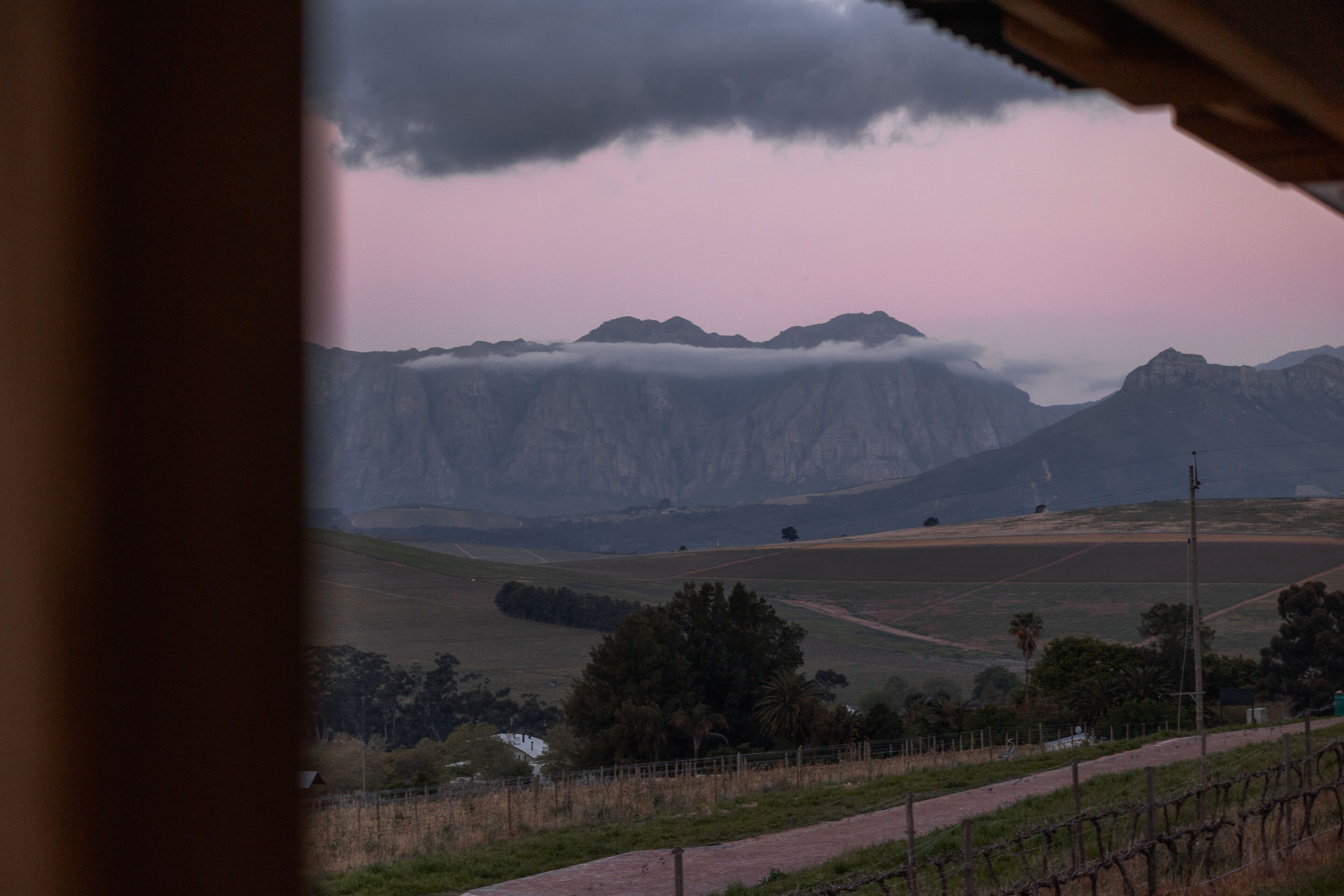 A rural landscape with mountains, a fence, and a road.