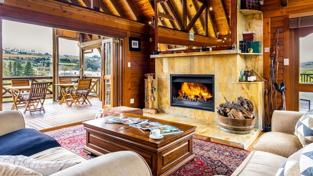 Ein gemütliches Wohnzimmer mit Kamin, Holzmöbeln und Blick ins Freie.