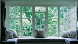 A room with a large bay window overlooking a garden. - High Hopes (Greyton)