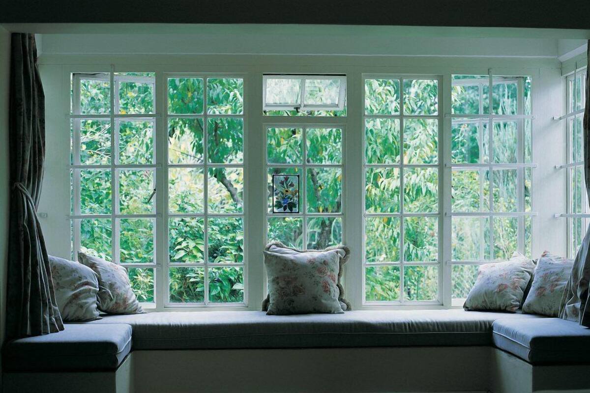 A room with a large bay window overlooking a garden.