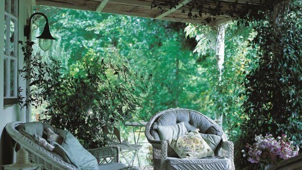 A covered outdoor seating area with wicker furniture and a view of lush greenery. - High Hopes (Greyton)