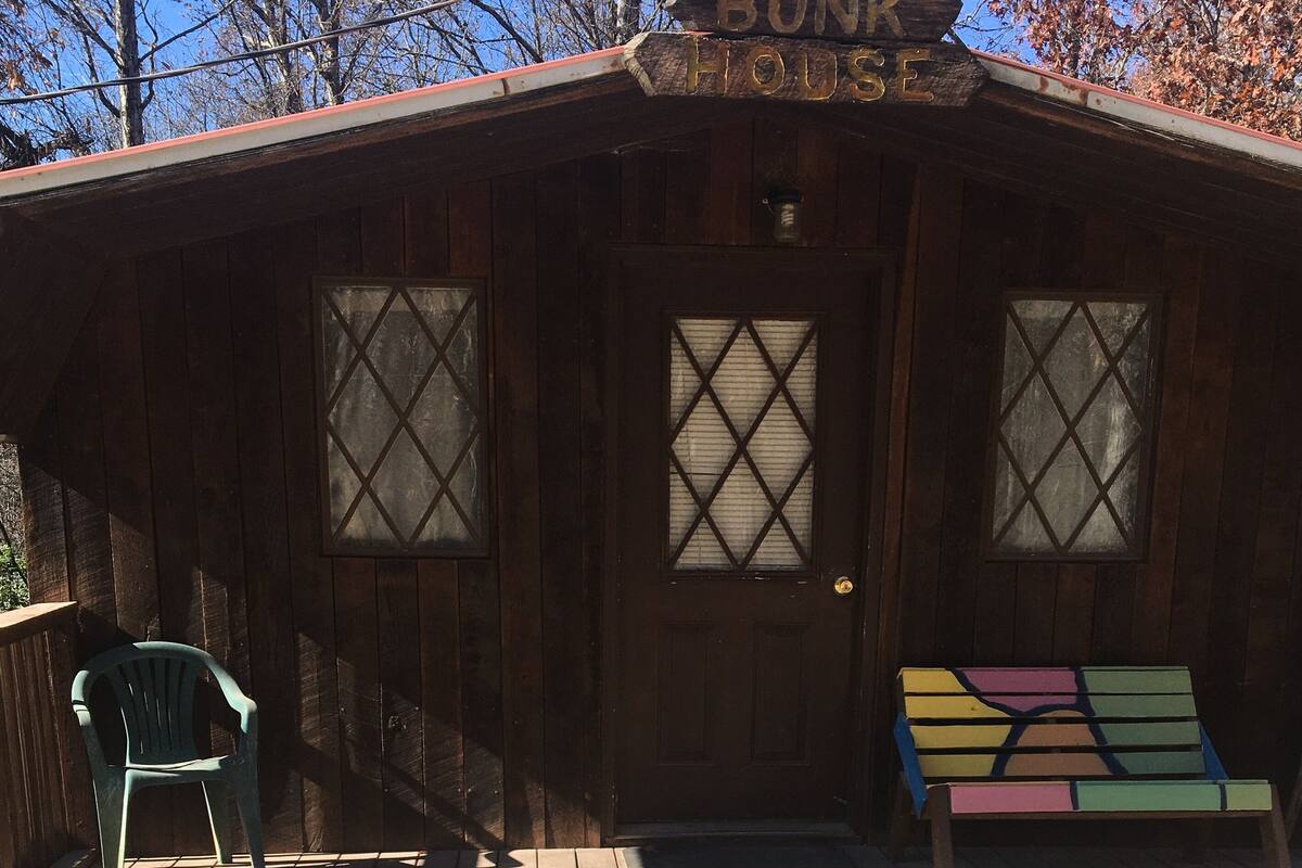 Une cabane rustique avec une façade en bois, une porte d’entrée et un porche agrémenté d’un banc coloré.