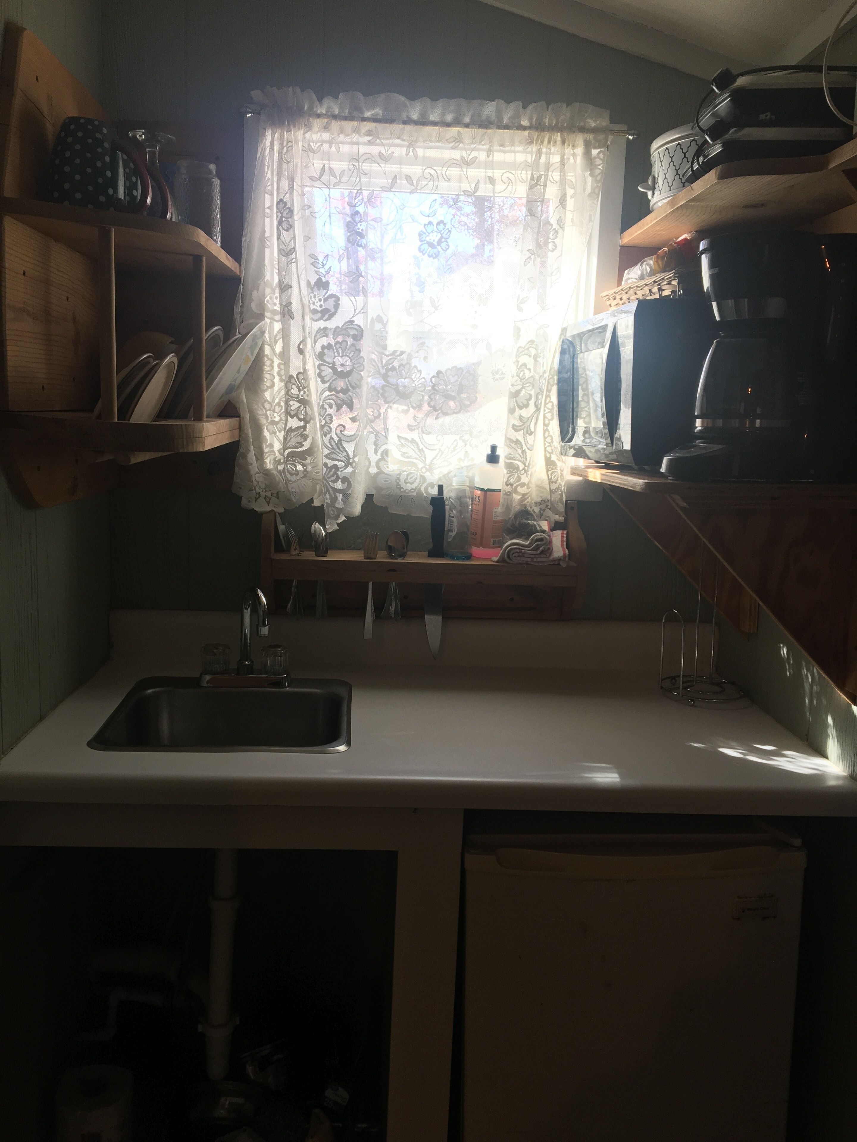 Una cocina funcional con lavamanos, microondas y cafetera.