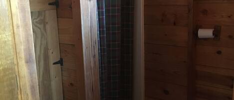 Baño de cabaña de madera con ducha, inodoro y radiador.