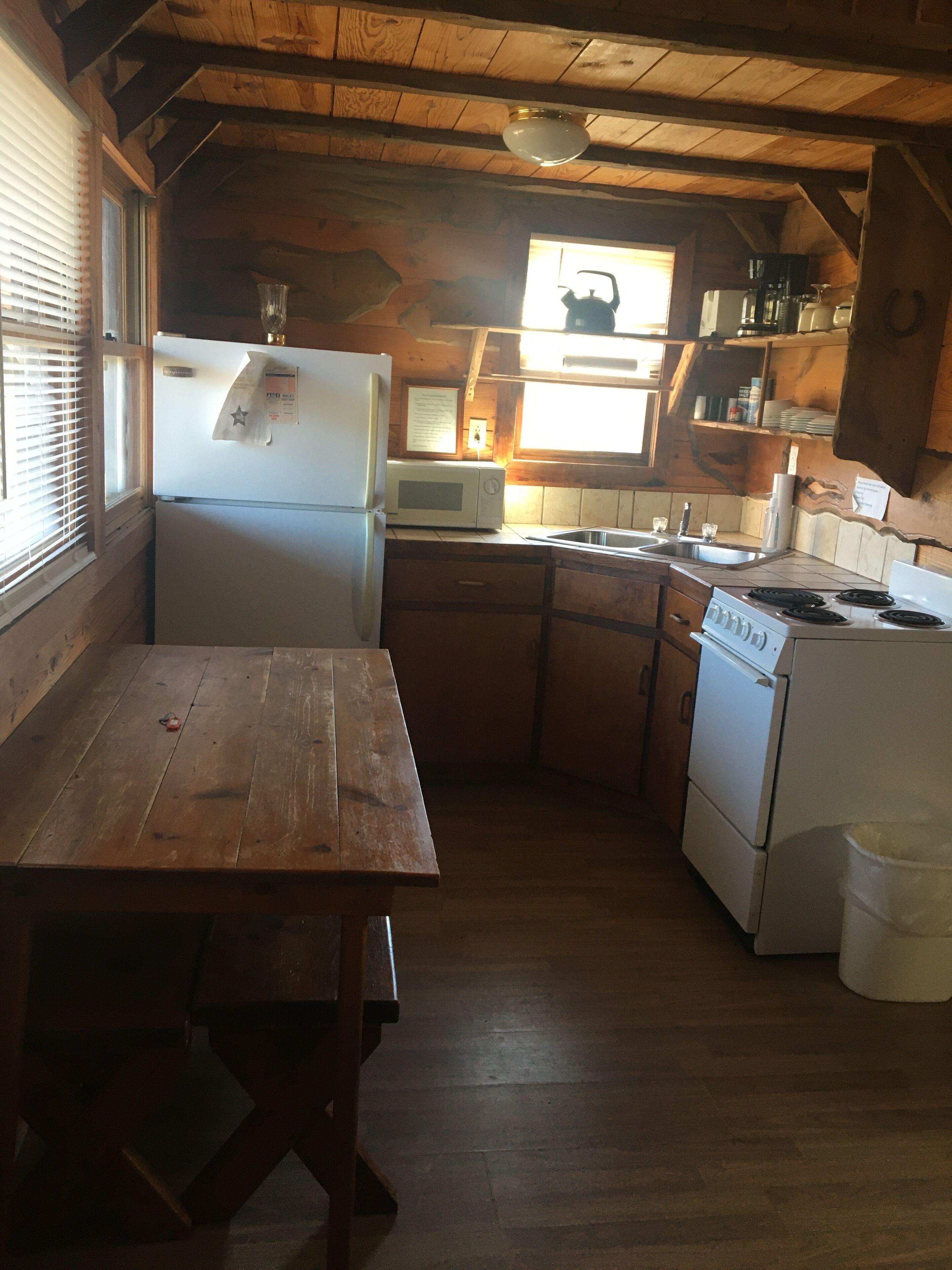 Una cocina compacta con armarios de madera, un refrigerador, un microondas, un fregadero y una estufa.