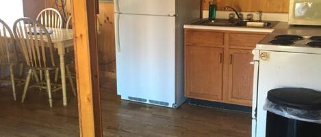 A kitchen with wooden cabinets, a refrigerator, a microwave, and a sink.
